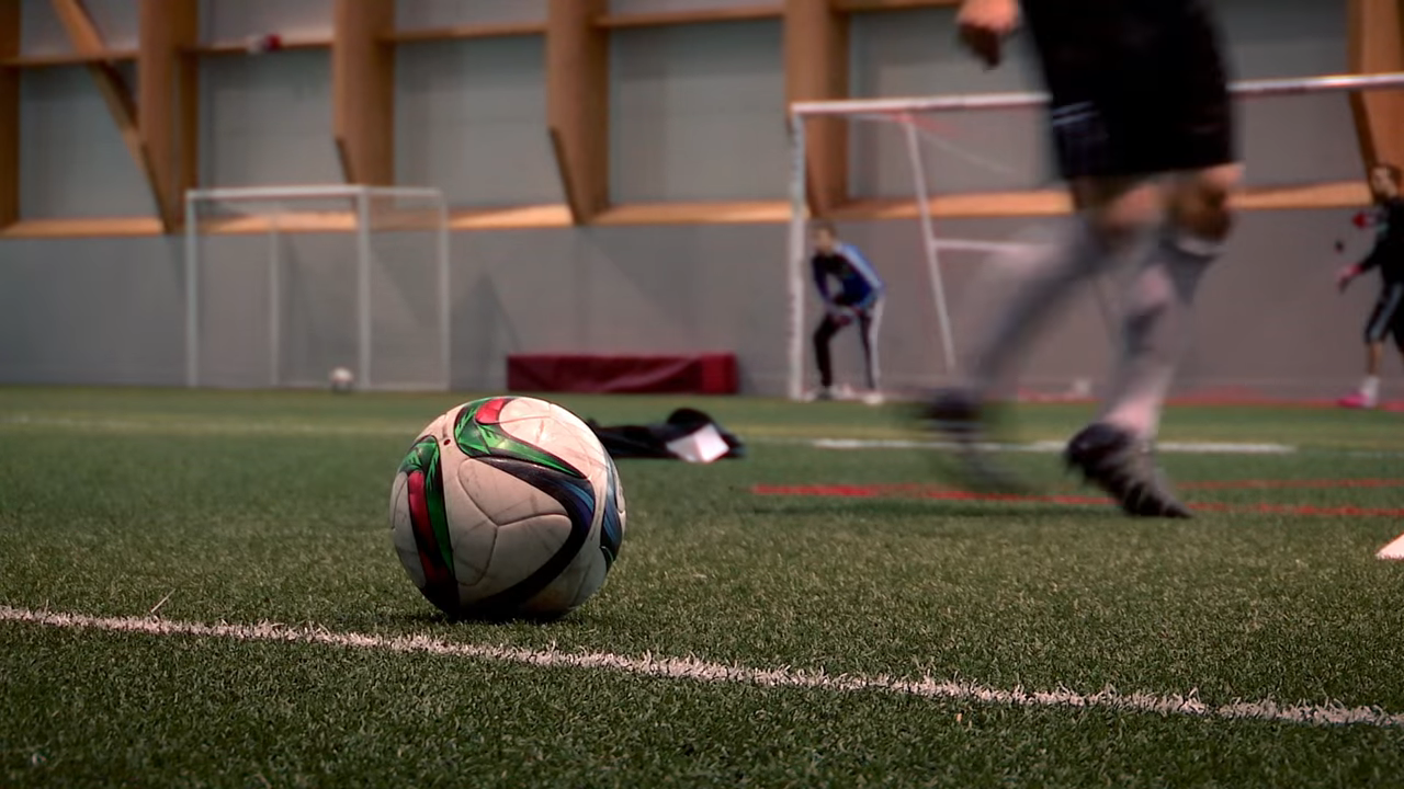 Ballon de soccer avec des joueurs qui s'entraînent en arrière plan