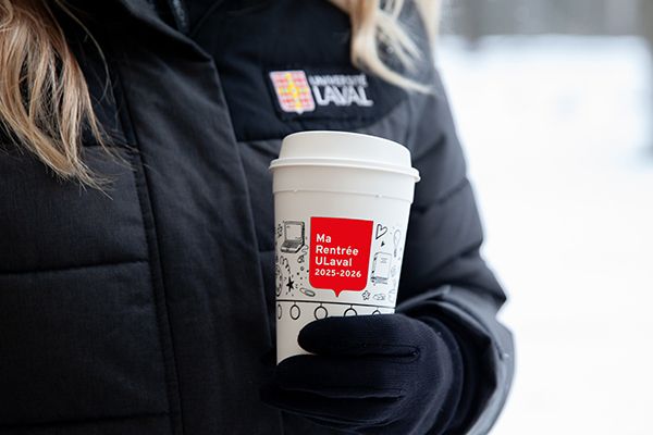 Personne tenant une tasse de la Rentrée ULaval dehors en hiver