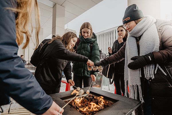 Étudiants autour d'un foyer faisant griller des guimauves