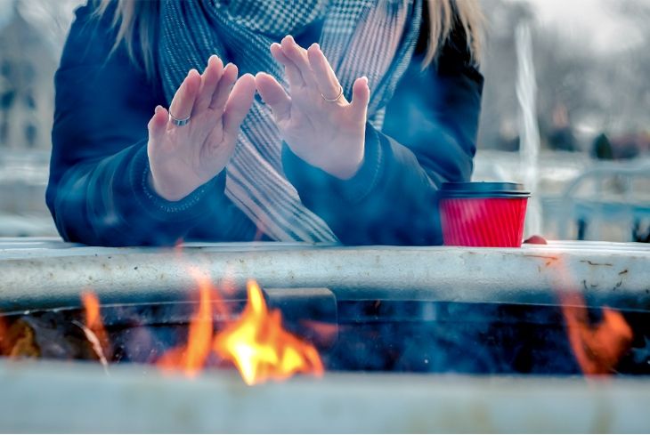 femme qui se réchauffe les mains près d'un feu