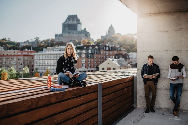 étudiante assise sur un banc et la ville de Québec en arrière-plan