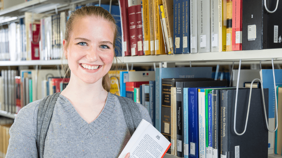 Jeune femme avec livre à la bilbiothèque