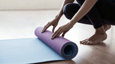 Personne déroulant un tapis de yoga sur le sol