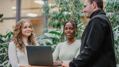 Deux étudiants et un conseiller autour d'une table avec un ordinateur portable